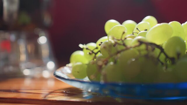 Close up of fresh green grapes on blue glass plate, resting on wooden table under soft natural light, background softly blurred with bokeh