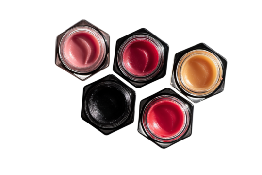 A group of five different lip balms in black glass jars arranged on top of each other to form the shape of an octagon with isolated on a transparent background in PNG format.