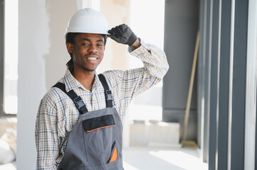 Smiling african american construction worker adjusting hardhat on site
