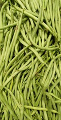 Fresh green beans piled high, showcasing their natural texture and vibrant green color. Ideal for healthy food, farm-to-table, and culinary themes.