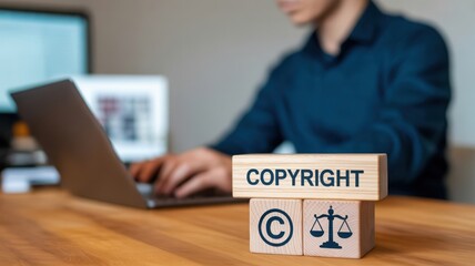 Protecting Digital Copyright: A person working on a laptop with wooden blocks displaying copyright and legal symbols, illustrating intellectual property protection and creative ownership