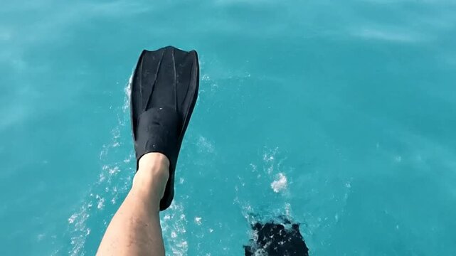 Black flippers and a pale leg are visible above turquoise water Ripples and bubbles are created by movement