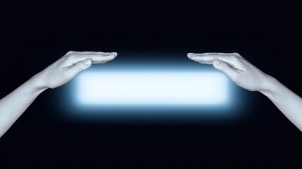 Two open hands facing each other above a glowing rectangle in a dark environment The hands are pale and the light is