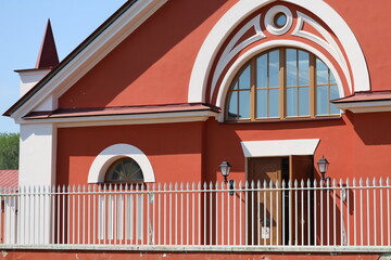 A large red building surrounded by a white fence, suitable for use in real estate or architecture photography