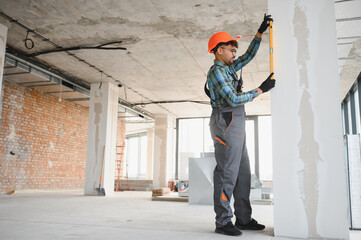 Arab engineer measuring wall with spirit level at construction site