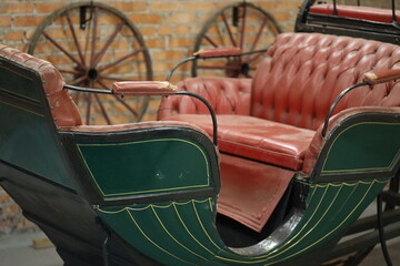 A vintage green and red carriage sitting in front of a brick wall, perfect for historical or nostalgic settings