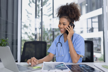 African American female doctor using mobile phone with laptop working at clinic office, Medical and health care concept.