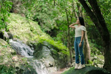 Serene Woman Enjoying Nature Near Waterfalls in Lush Forest Setting