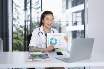 portrait of a confident female doctor using laptop sitting at working desk in hospital, Medical and health care concept.
