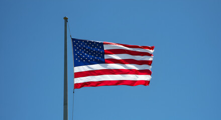 Fototapeta premium United States Flag Waving Proudly Against a Brilliant Blue Sky Backdrop