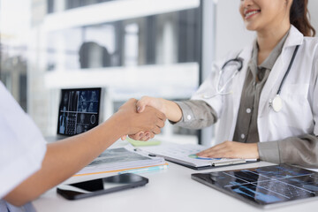 Two female doctors shaking hands in meeting room at hospital, Healthcare and medical concept.
