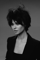 Black and white portrait of a young woman with short messy hair and serious expression wearing a dark jacket