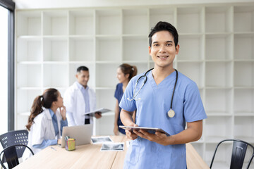 Obraz premium A young male doctor smiling looking at the camera in meeting room, Medical team reviewing data. 