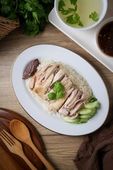 Chicken and rice with coriander and cucumber with sauce and soup in a white plate, hainanese chicken rice, thai called khao man gai, asian food, thai food