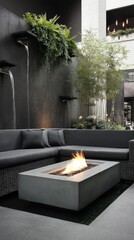 Modern outdoor fire pit in a stylish, dark-toned indoor courtyard.  Plants, lush greenery, and a sectional sofa surround the grey concrete fire pit