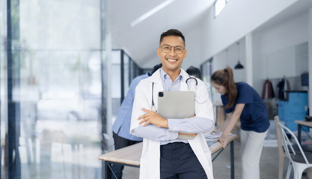 A male doctor smiling looking at the camera in meeting room, Medical team reviewing data.