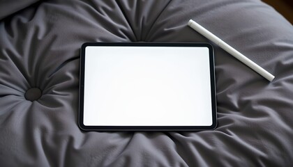 Fototapeta premium Digital tablet with a stylus pen on a soft gray blanket, top view.