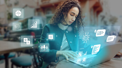 Young professional working on laptop with digital icons overlay in modern office environment