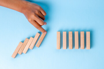 Human Finger Blocks Wooden Domino Chain Reaction Before It Continues, Showing Prevention