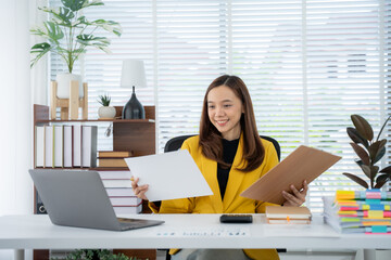 Focused professional at her desk: A focused young woman dressed in a stylish yellow suit, absorbed...