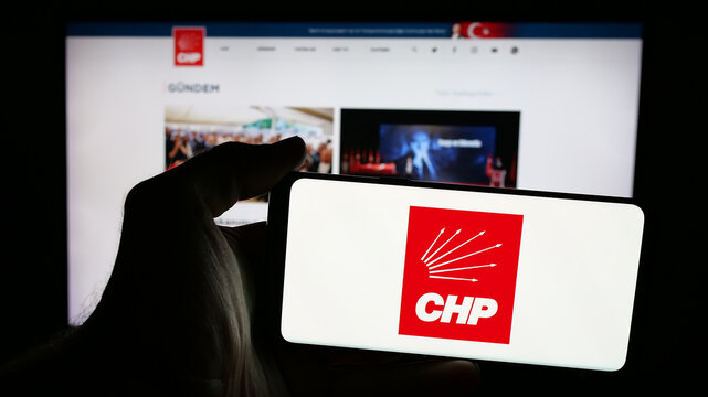 Stuttgart, Germany - 07‑23‑2025: Person holding mobile phone with logo of Turkish party Cumhuriyet Halk Partisi (CHP) on screen in front of web page. Focus on phone display.