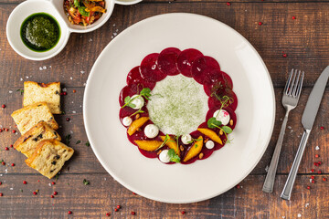 Beet carpaccio with orange slices, fresh greens and cream dots