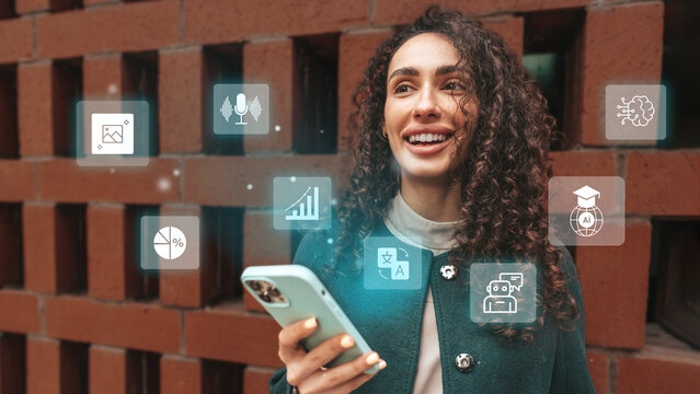 Young woman smiles while using smartphone in front of brick wall with digital icons representing technology and education