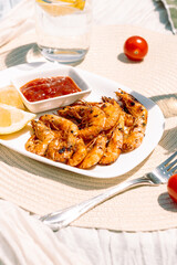 Juicy grilled shrimp with lemon juice, garlic, and melted butter, served with fresh lemon wedges and tangy cocktail sauce on a white plate, healthy gourmet seafood.
