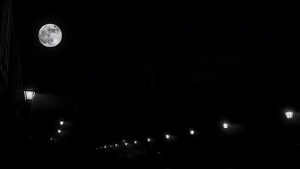 A dark night scene with a full moon above a row of street lamps illuminating the empty street below