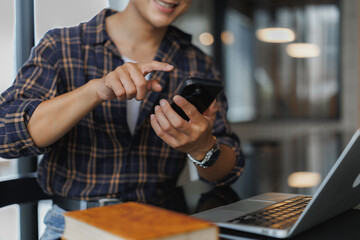 Student using smartphone and laptop in modern library, enjoying learning and connectivity