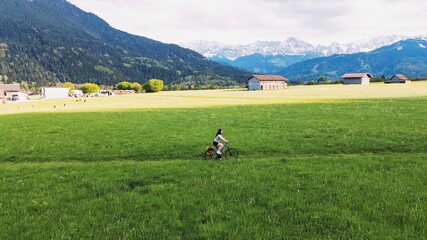 Happy female cyclist in green mountain meadow
