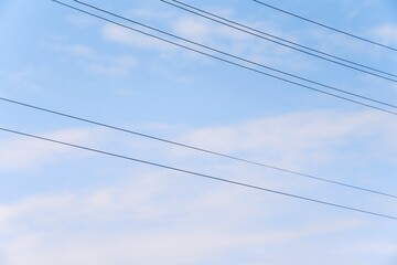 Fototapeta premium Power cables crossing soft cloud sky