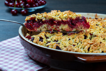 Baking dish with tasty cherry pie, closeup. Delicious homemade pie with fresh red cherries on wooden table. Summer shortcrust pie with berries