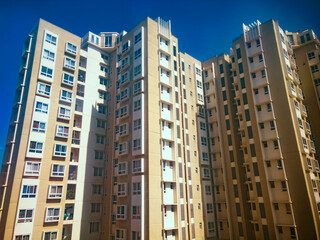 Modern apartment buildings rise against a vibrant blue sky in Bengaluru, India, creating a striking...