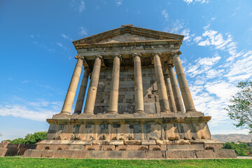 Fototapeta premium Garni Temple, a first-century hellenistic ionic temple near Garni, Armenia, stands majestically against a vibrant blue sky, showcasing its well-preserved columns and intricate stonework