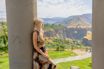 Blonde woman tourist leaning against a column of the Garni Temple, a hellenistic temple located in...