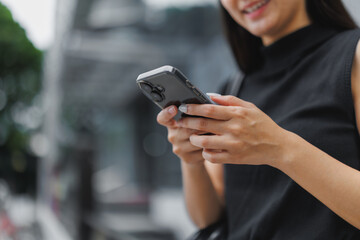 Businesswoman using smartphone in urban setting, smiling and browsing