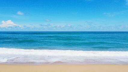 Serene Coastal View: A breathtaking panorama of a tranquil beach, with pristine white waves meeting the golden sands beneath a bright blue sky. The image is filled with the calmness of the ocean.