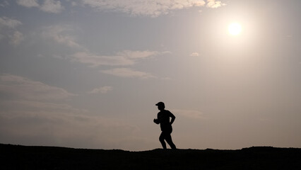 Silhouette of a Runner Against the Sun: A lone figure runs swiftly against the bright sun, creating a striking silhouette of determination.