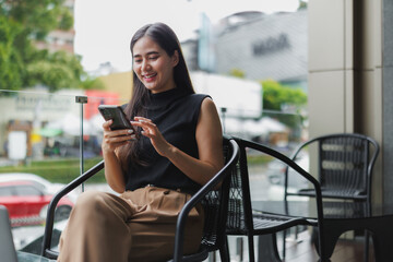 Smiling businesswoman using smartphone at outdoor cafe