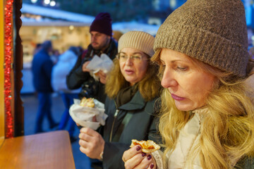 Women enjoying food at a Christmas market.