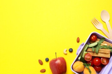 Healthy food concept with lunch box with fresh fruits, nuts, sandwich and vegetables