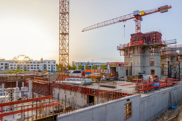 Construction site in Augsburg with cranes and scaffolding at sunset, showcasing housing development and energy-efficient buildings.