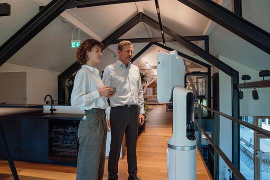 Business professionals collaborating with robot on technology development