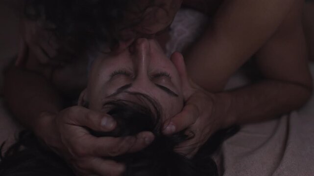 Sensual lovers kissing in bed, passionate woman enjoying pleasant sensations while man kisses her neck and lips. close-up view.