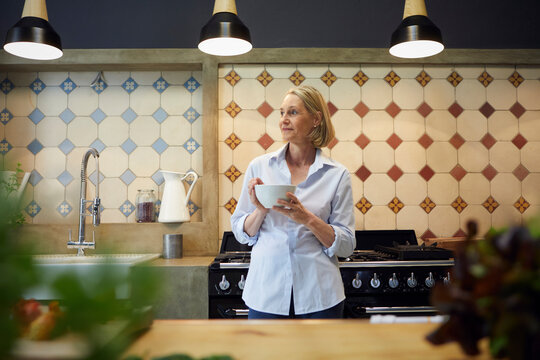 Woman relaxing with coffee in modern loft kitchen at home