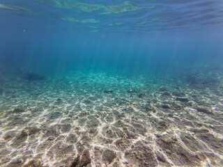 A serene underwater landscape of the rocky and sandy seabed in the clear turquoise Mediterranean Sea of Calanques, Marseille, France.