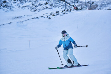 Confident skier descending groomed slope on winter mountain
