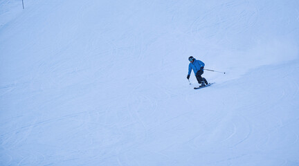 Telemark skier carving fast turns on snowy slope in winter sunlight