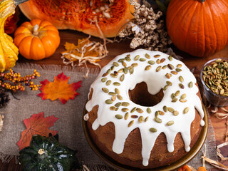 Pumpkin pound cake, topped with icing and pumpkin seeds, pumpkins and autumn leaves all around.
